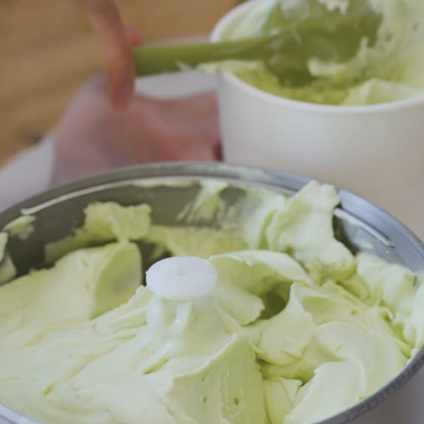 Avocado Ice cream in ice cream maker with ice cream container in the background