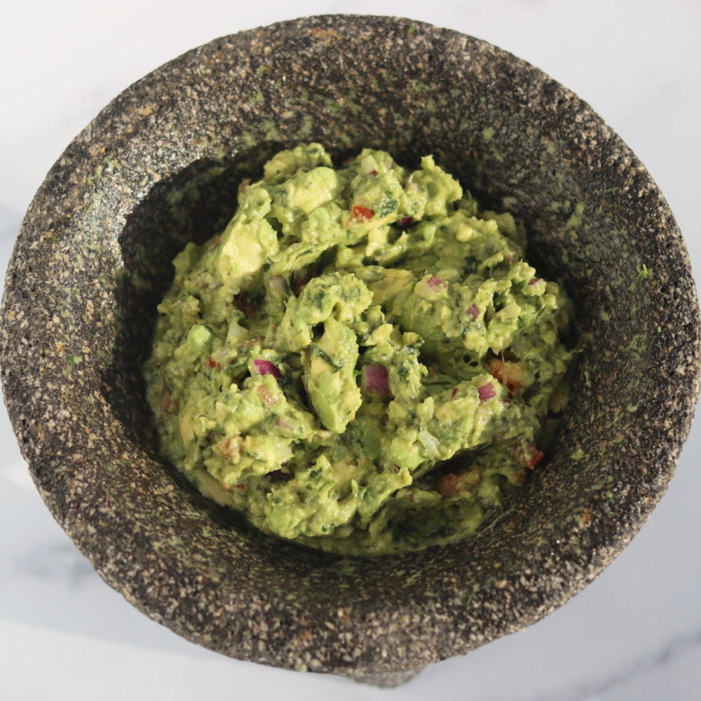 guacamole with onions ans tomatos in a rock bowl