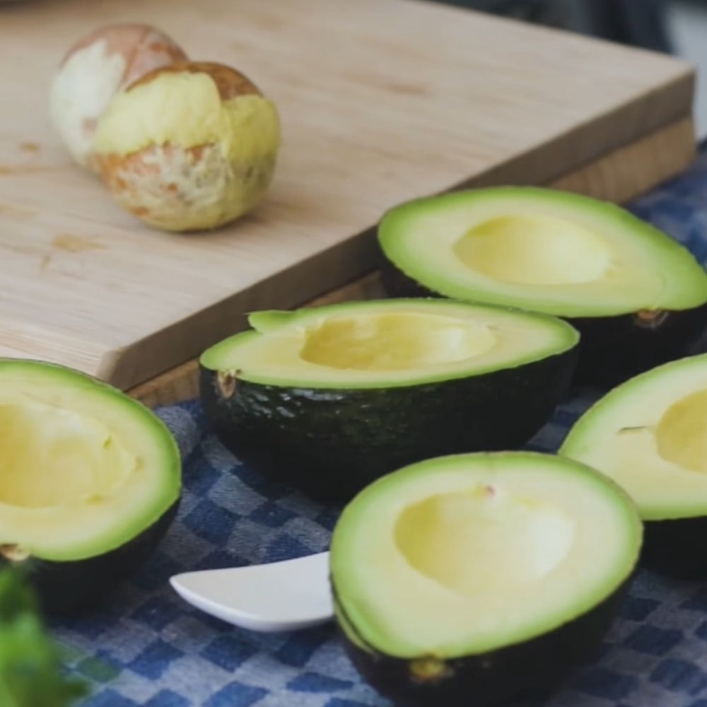 Avocado seeds on a cutting board next to open avocado halves