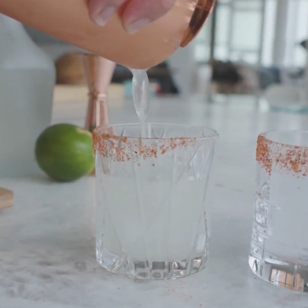 Pouring the perfect margarita into a whiskey glass with a spicy rim