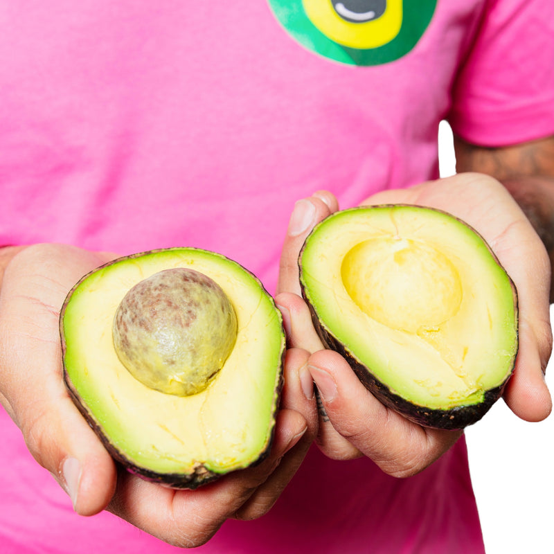 Davocadoguy wearing a Pink Davocadoguy Logo T-shirt, holding an open perfectly ripe avocado