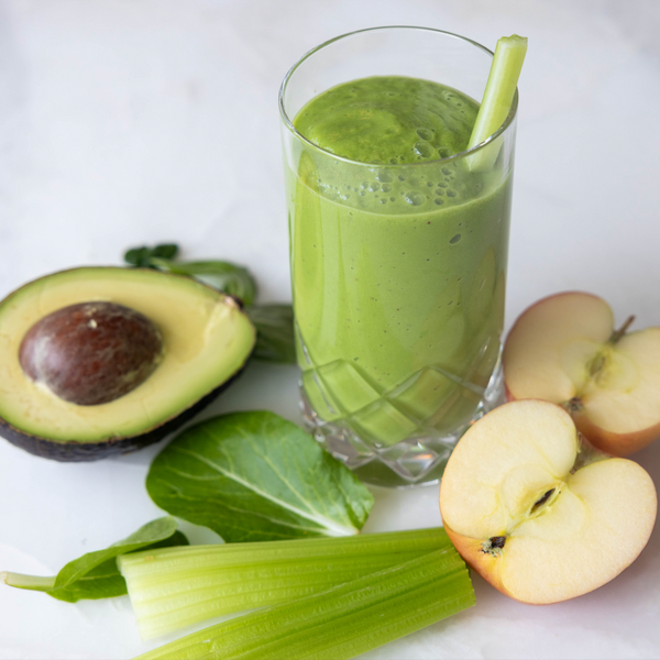 Detox green Smoothie - Avocado spinach celery apple displayed around smoothie glass