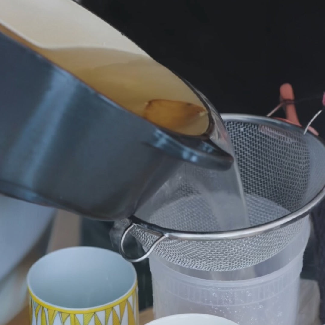 pouring liquid through a mesh strainer into a container