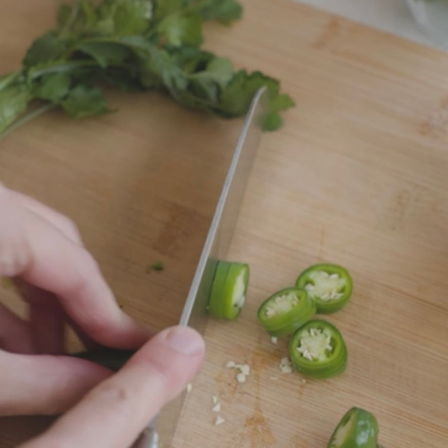 slicing green chili peppers on a cutting board