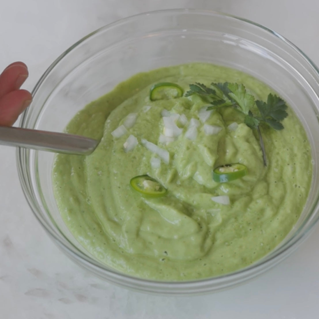 bowl of avocado soup garnished with sliced green chilies and cilantro