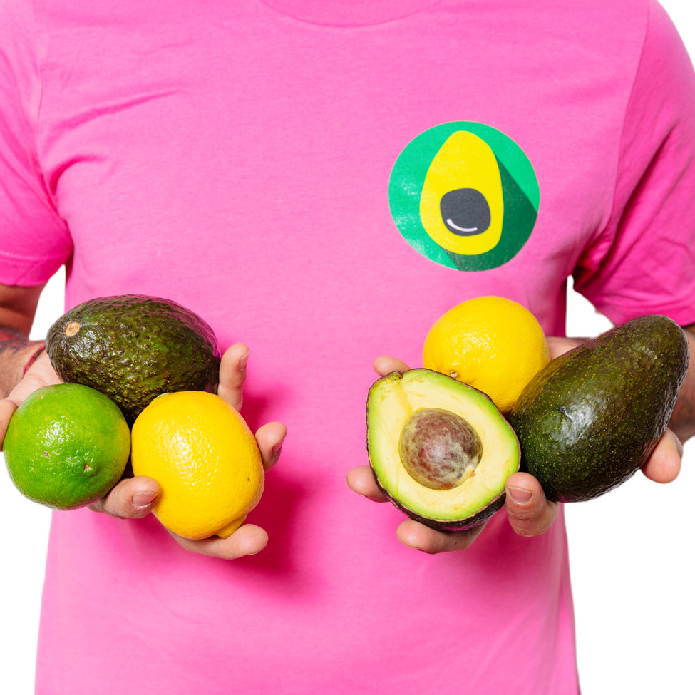 DavocadoGuy wears a pink DavocadoGuy t-shirt and holds limes, lemons and avocados in his hands