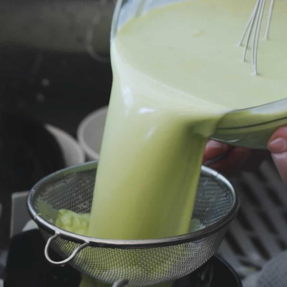 pouring blended avocado miture through a strainer to make ice cream