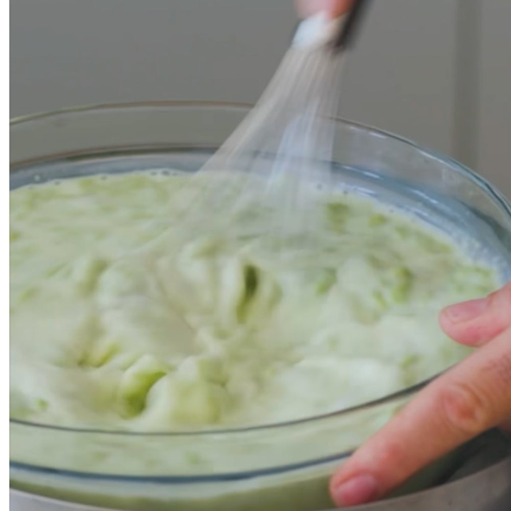 whisking a creamy mixture in a glass bowl