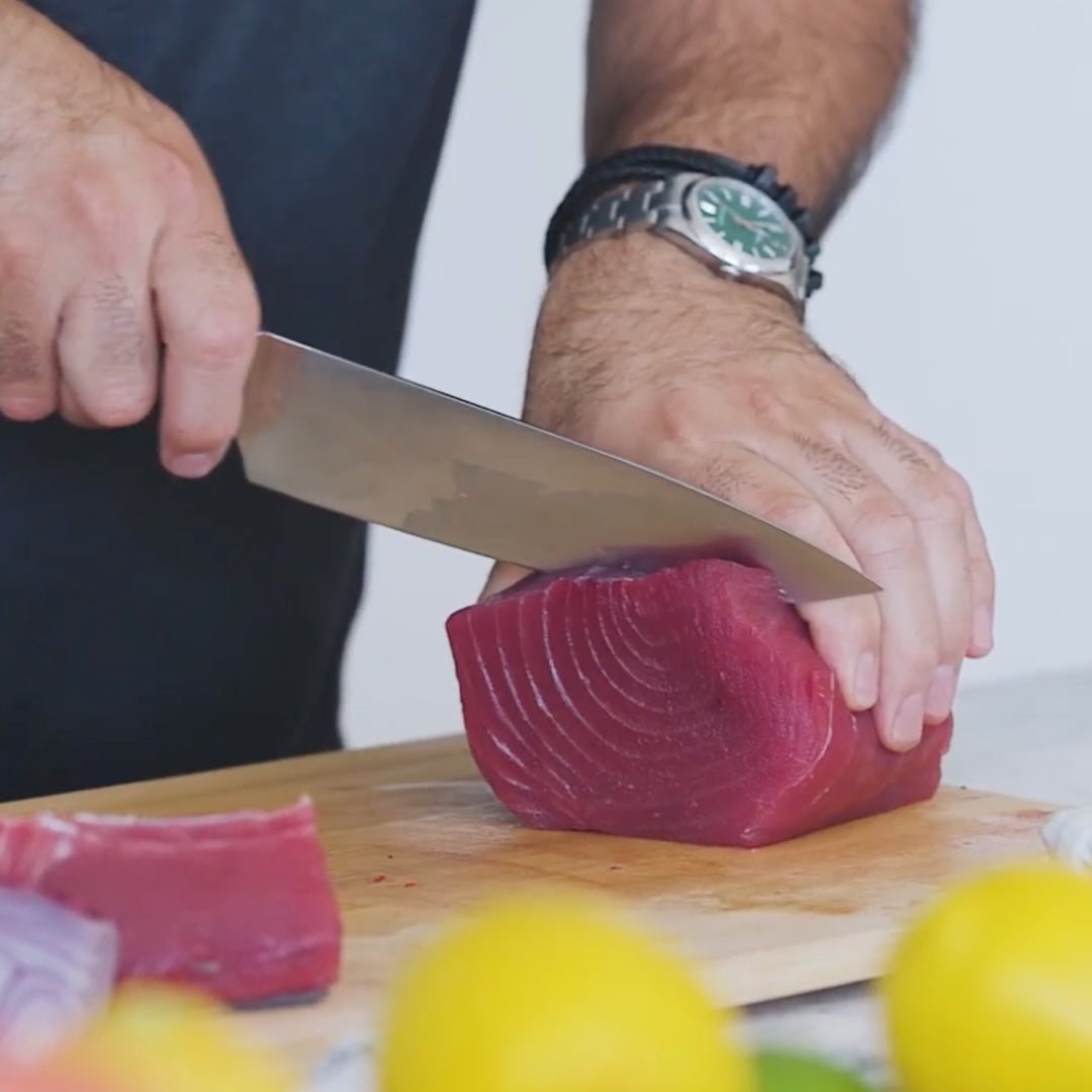 slicing a piece of raw tuna on a cutting board
