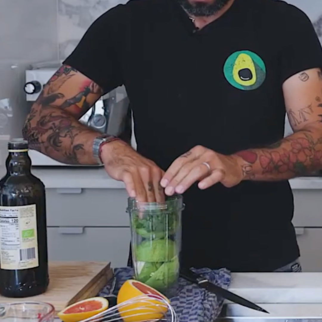 placing ingredients into a blender, with avocados and other items visible on the counter