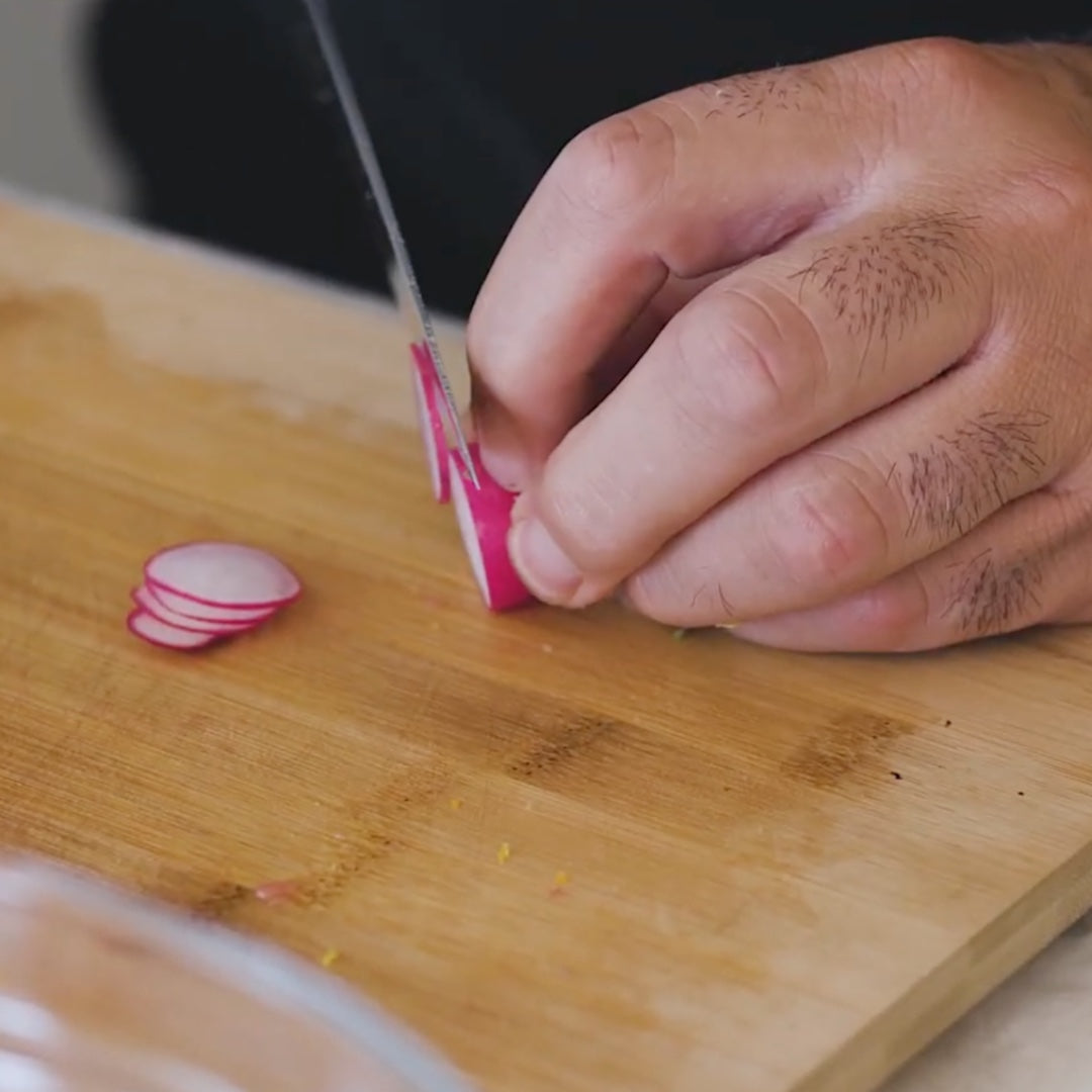 slicing a radish on a wooden cutting board