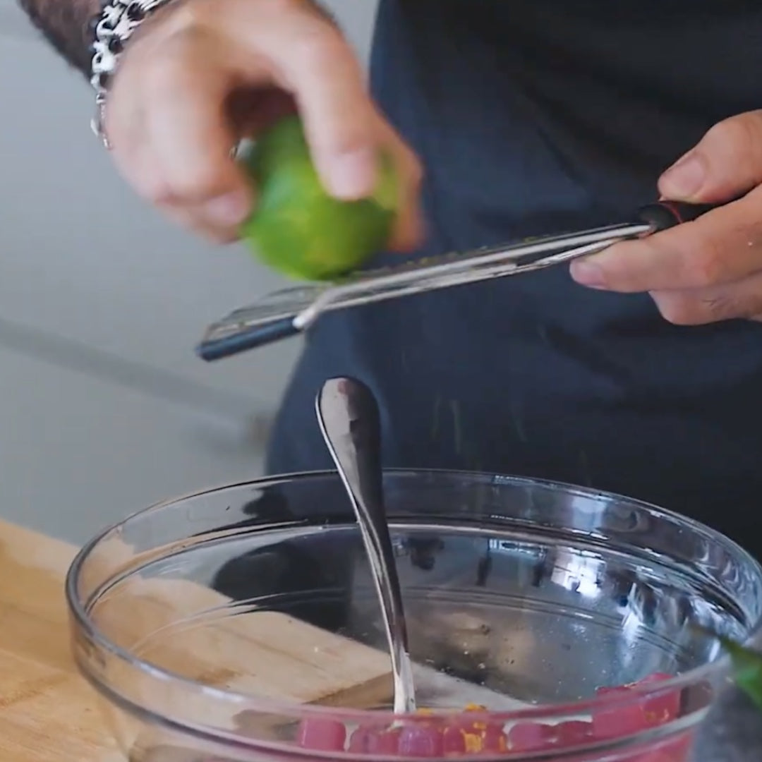 zesting a lime into a bowl with a spoon
