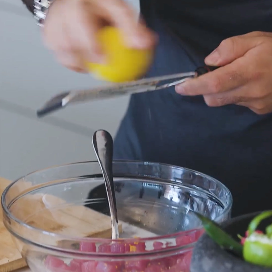 zesting a lemon into a bowl with a spoon