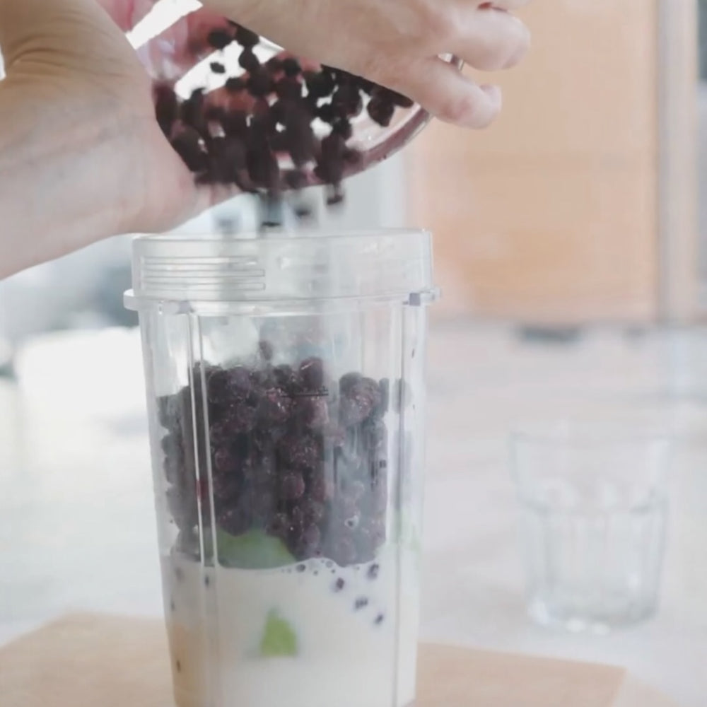 adding blueberries into a blender jar with other ingredients