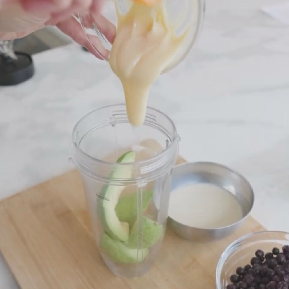 pouring a creamy mixture into a blender jar with avocado slices