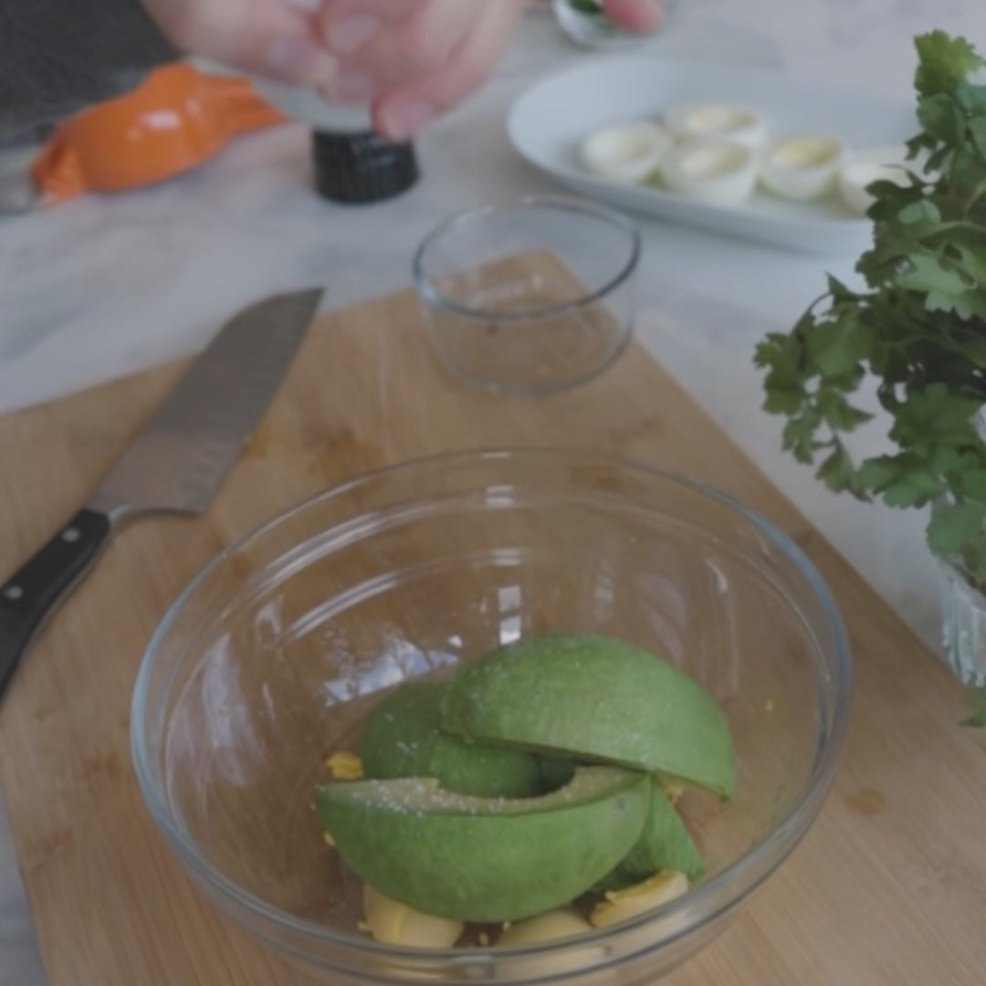 avocado slices and garlic cloves in a bowl, with cilantro nearby