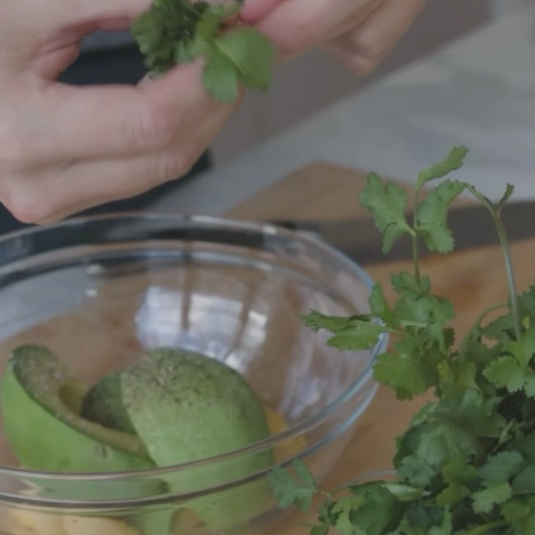 chopping cilantro next to a bowl with avocado halves