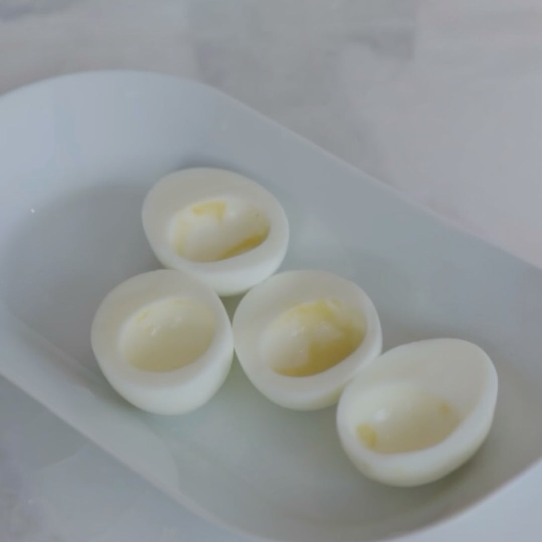 four peeled hard-boiled eggs in a container