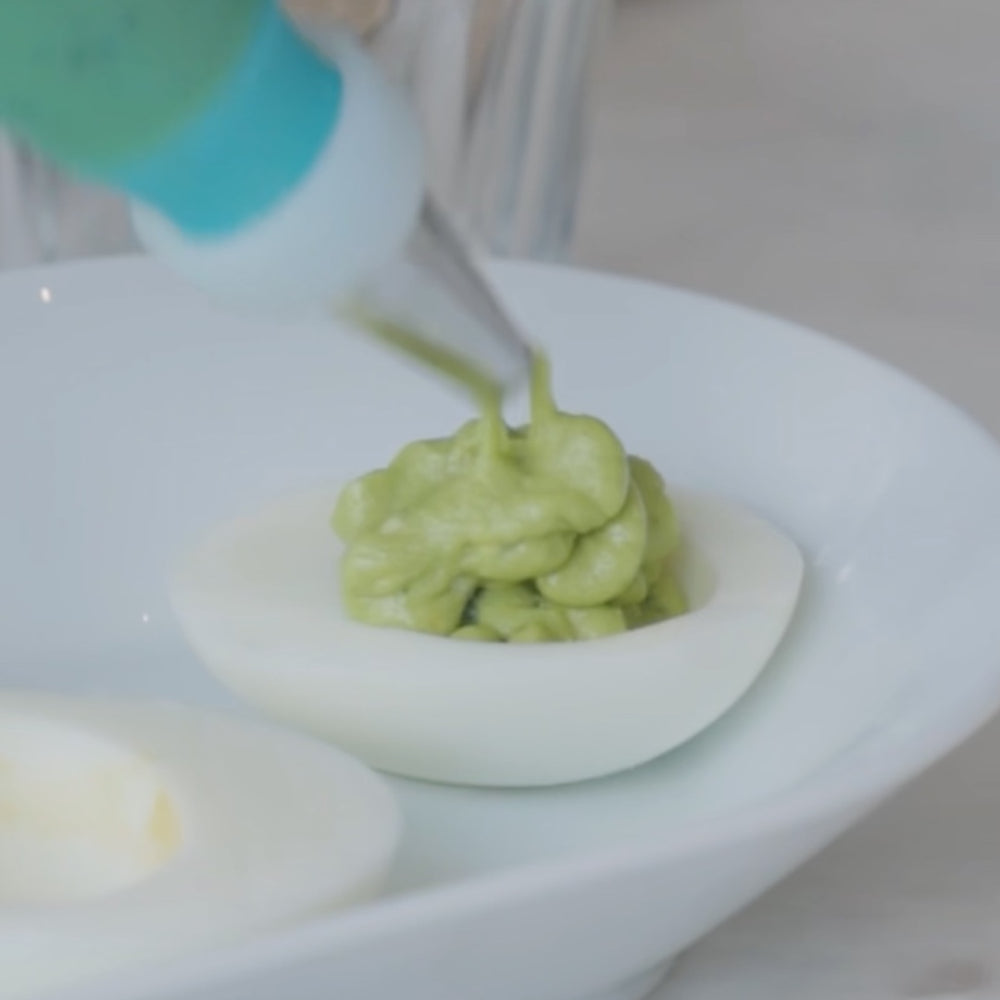serving mashed avocado in hard-boiled eggs onto a plate in