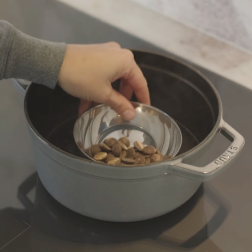 adding almonds from a bowl into a pot