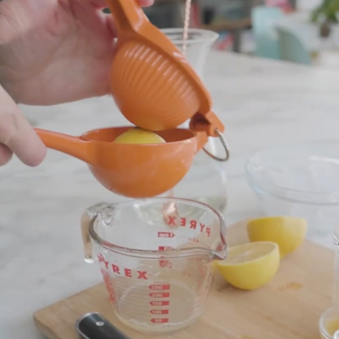 using a citrus juicer to squeeze a lemon over a measuring cup