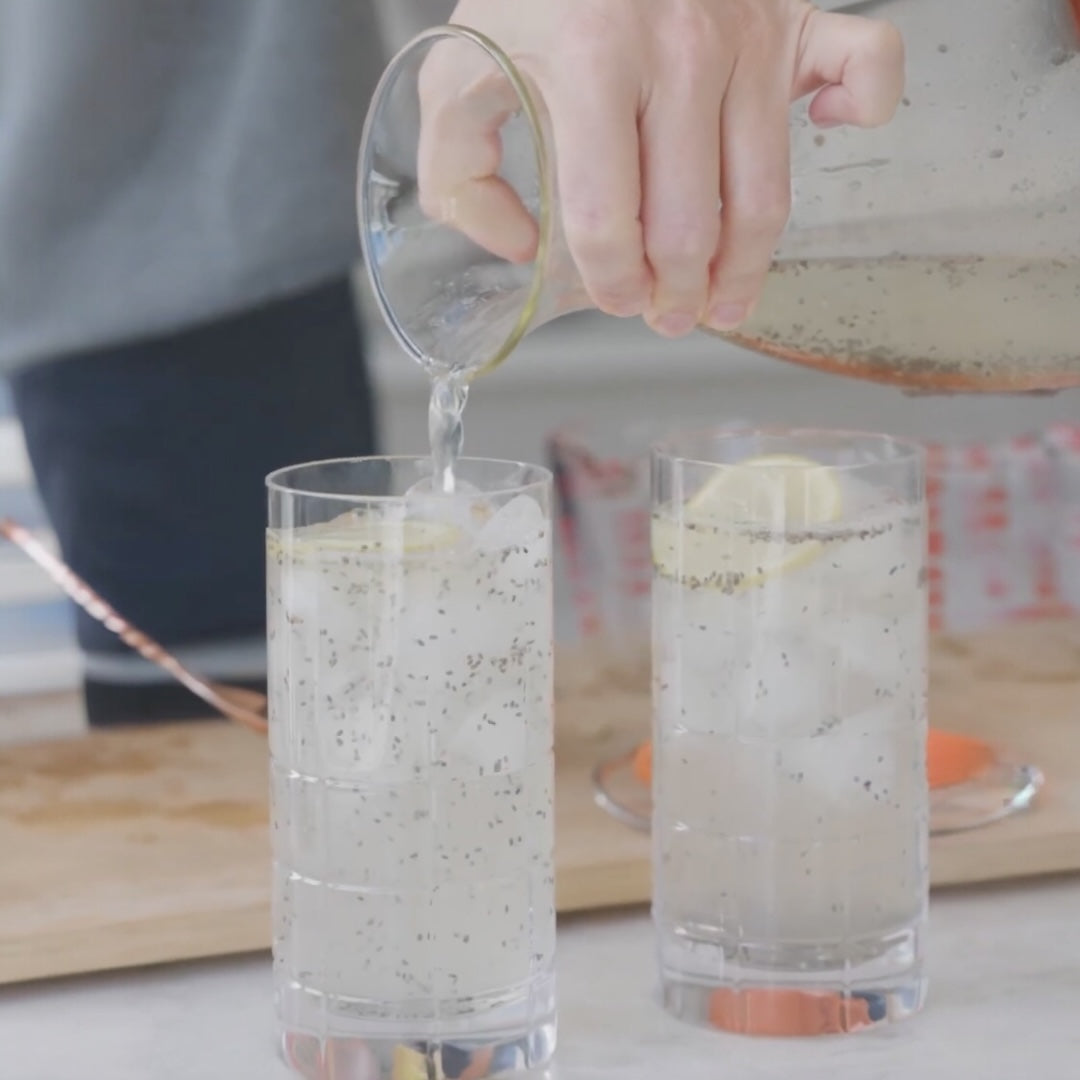 pouring a clear liquid into a glass with ice cubes