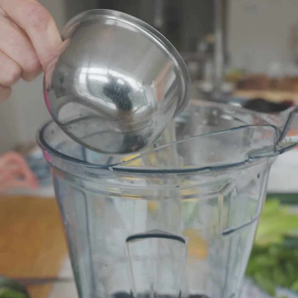 liquid being poured from a metal cup into a blender