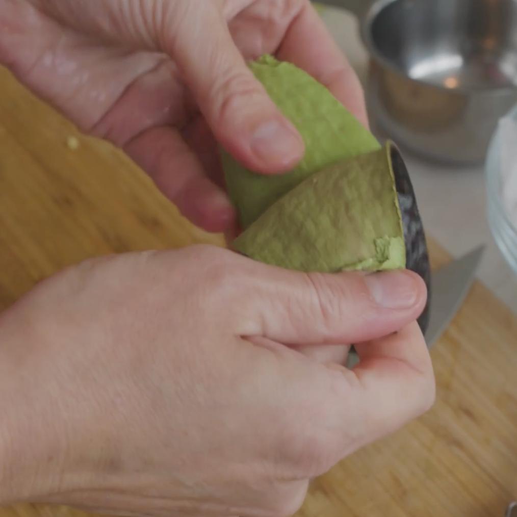 a person holding an avocado, preparing to cut or open it
