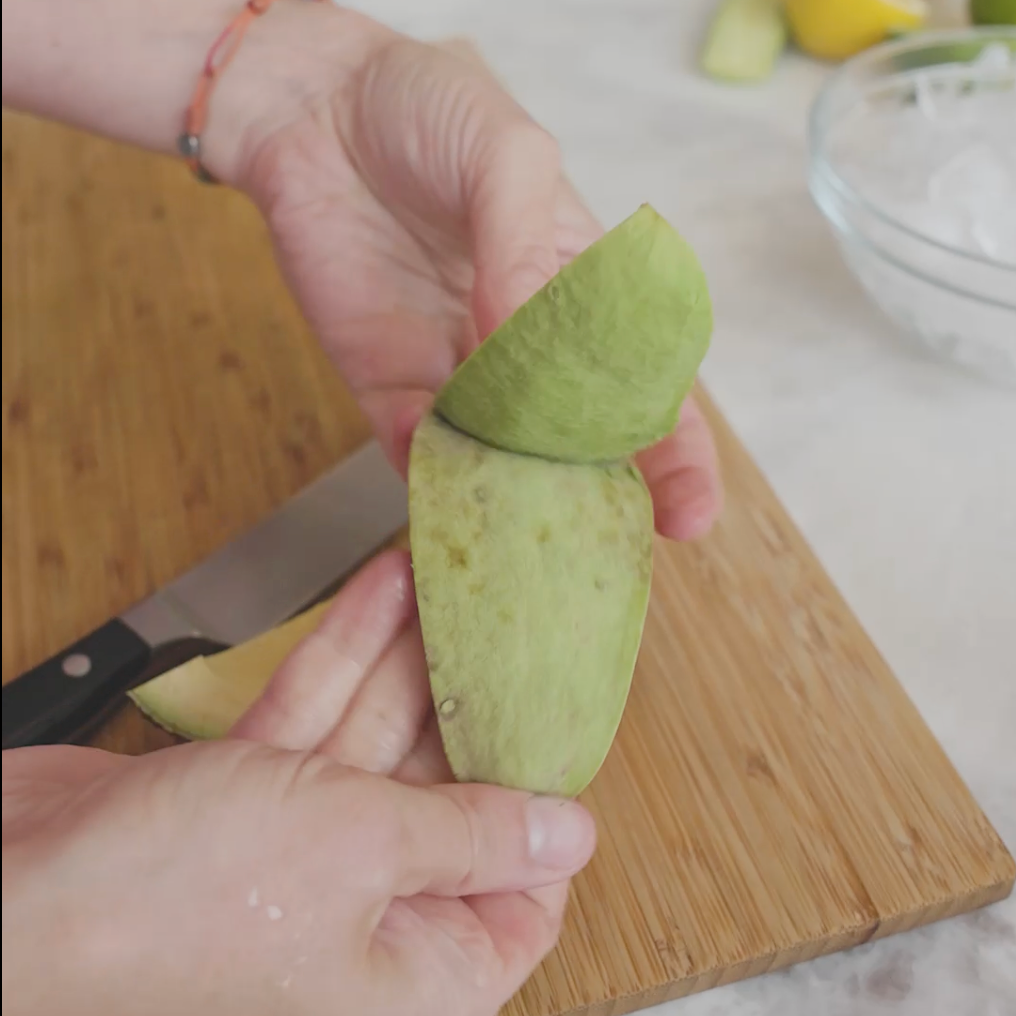a person cutting an avocado on a wooden cutting board