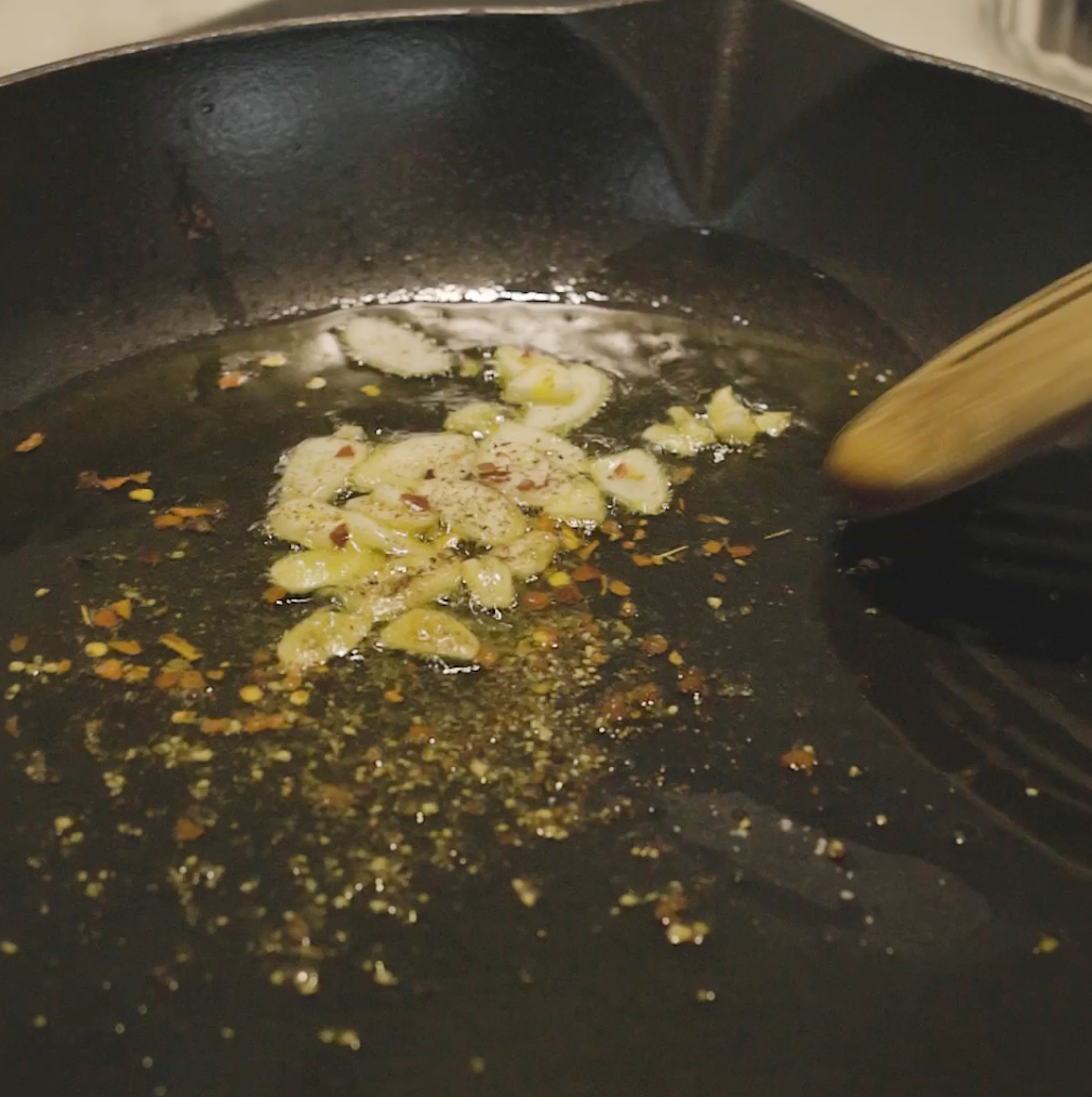 sliced garlic being sautéed in a pan