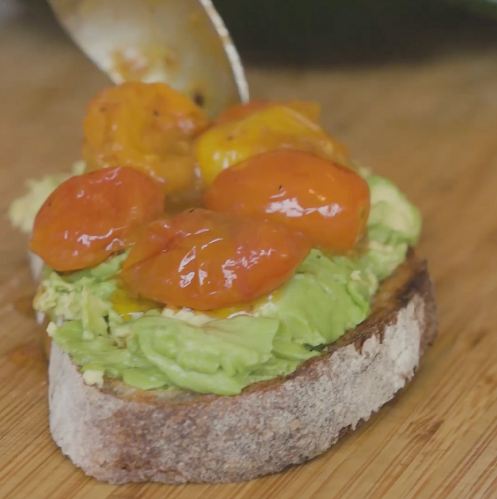 a slice of bread topped with mashed avocado and roasted cherry tomatoes