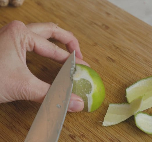 slicing a lime on a cutting board