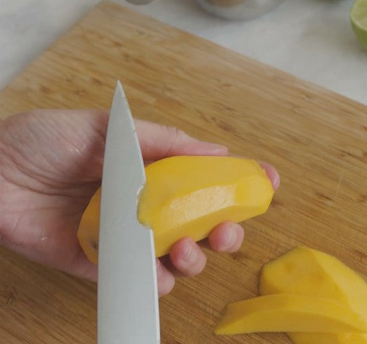 peeling a mango with a knife