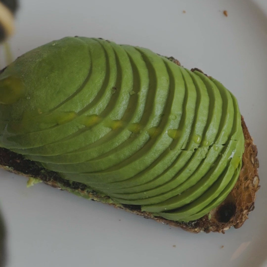 a slice of bread topped with thinly sliced avocado, arranged neatly