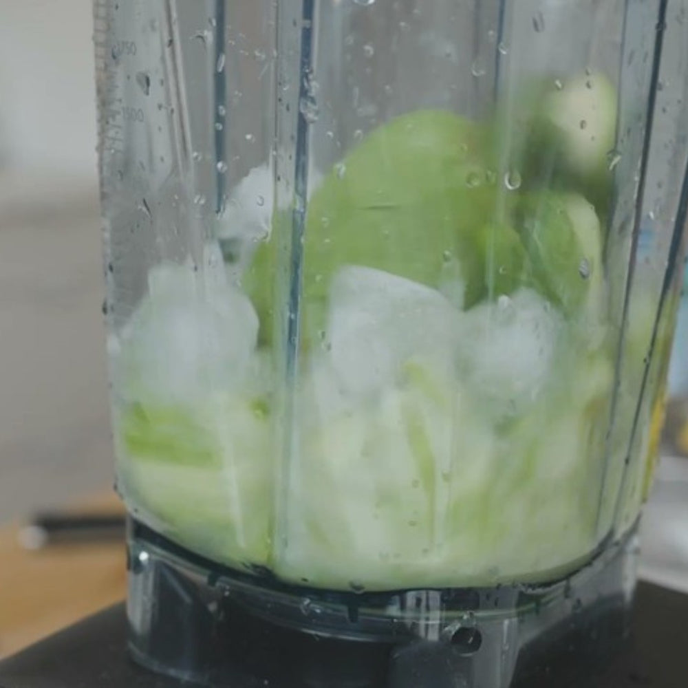 ingredients, including ice and avocado, in a blender