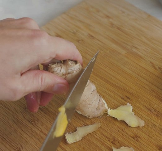peeling ginger on cutting board