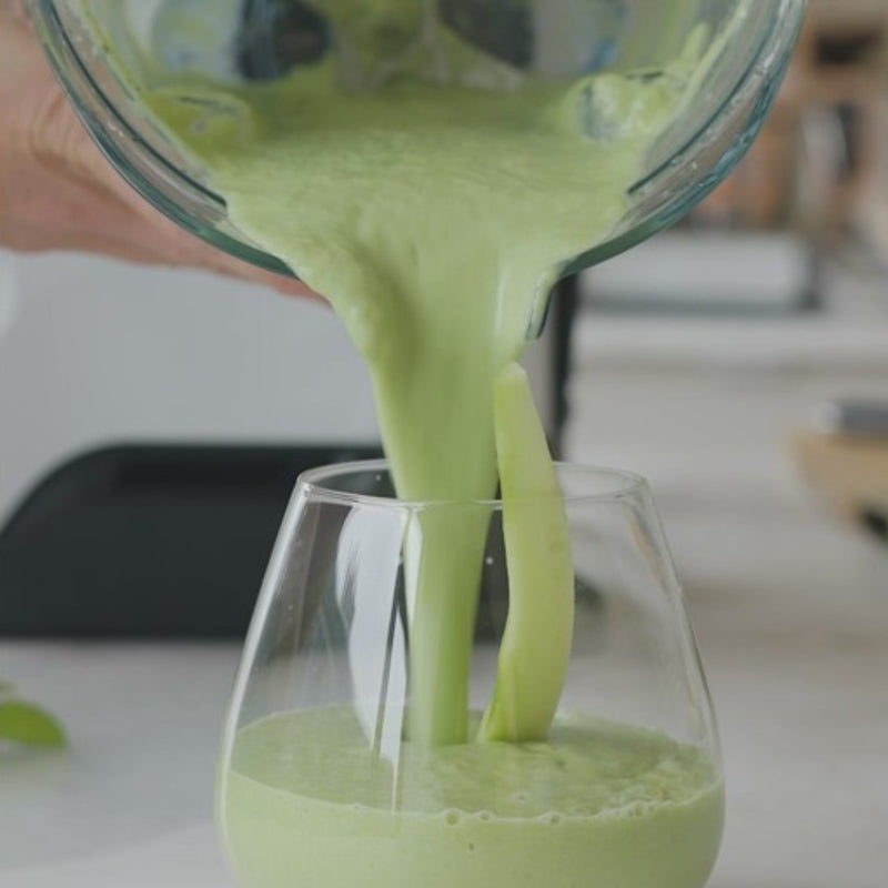pouring a green smoothie into a glass