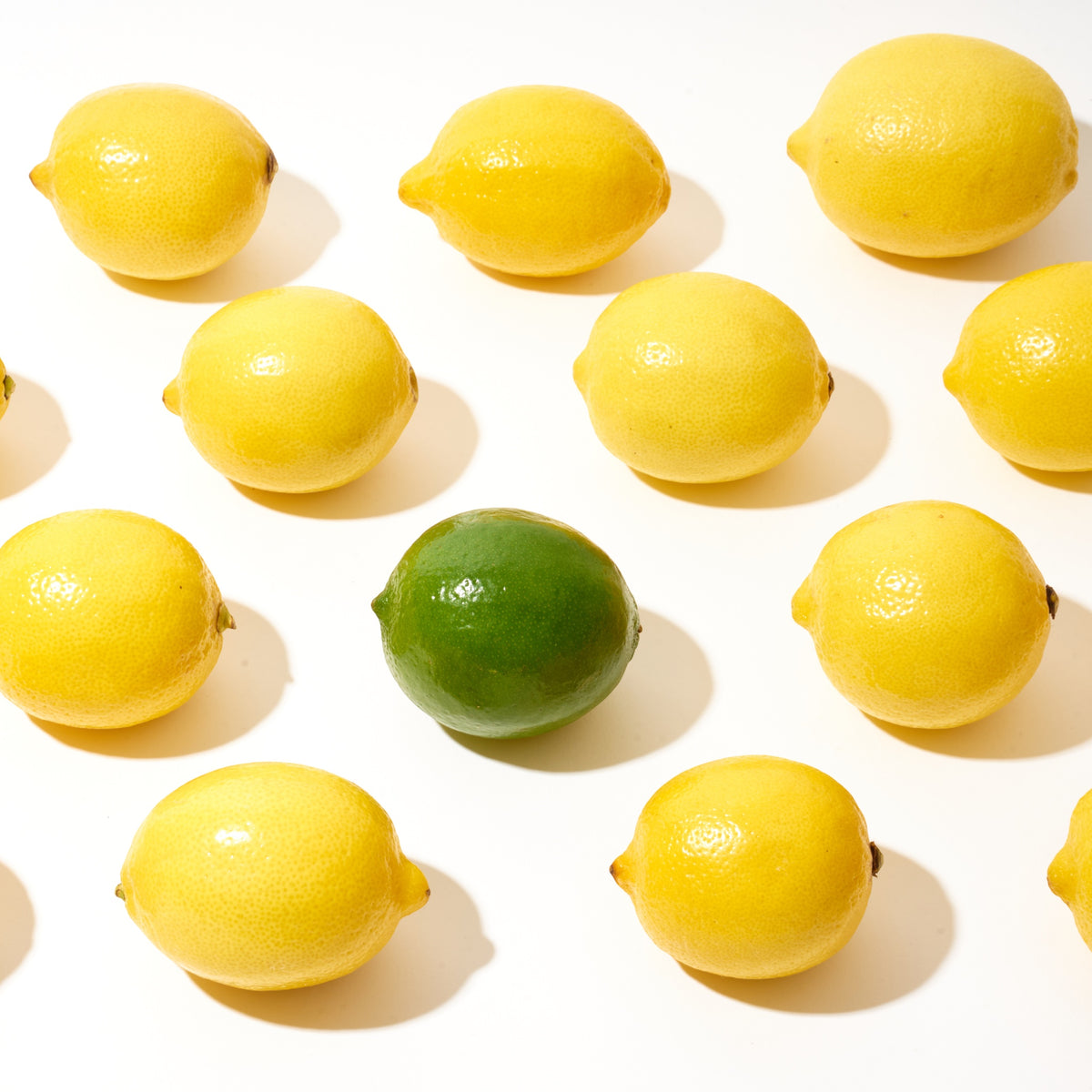 Lemons on a table with a fresh lime in the center.